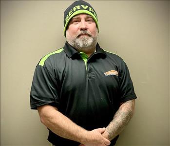 SERVPRO male employee with a black SERVPRO shirt, khaki pants, and a green and black SERVPRO beanie.