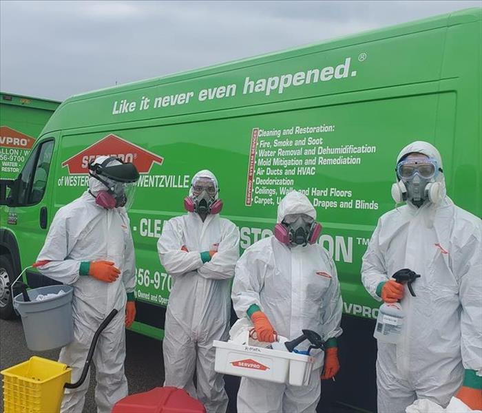 Employees in front of SERVPRO box truck in full ppe